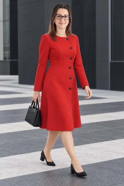 Queen Rania | CAQA Groups Queen Rania of Jordan walks across a crosswalk in a red dress, showcasing professional business attire.